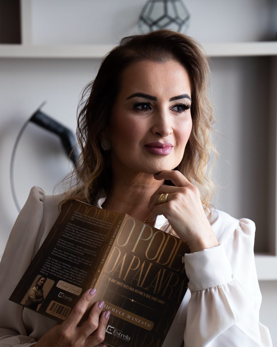 Michelle Manzato, sentada, segurando o livro O Poder da Palavra